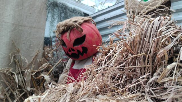 Halloween ghost behind a haystack whose head is made of pumpkins at an event
