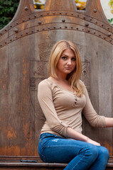Portrait of a young woman with long blonde hair sitting on a big wooden throne