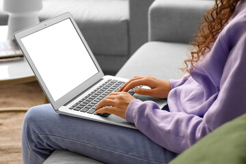Fototapeta premium Young woman using laptop on sofa at home, closeup
