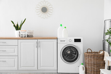 Interior of light laundry room with washing machine, counters and basket