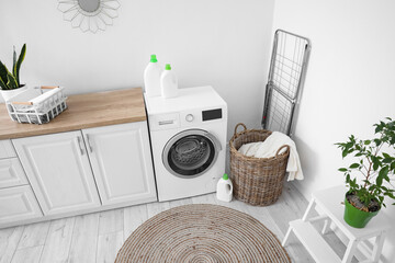 Interior of light laundry room with washing machine, counters and basket