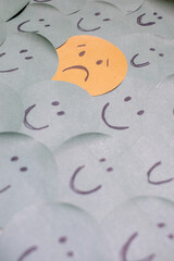 a sad face around happy faces - paper drawing
