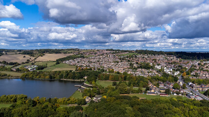 Fototapeta na wymiar Aerial drone photo of the large Worsbrough reservoir in the village of Worsbrough, Barnsley in Sheffield in the UK, showing the British village and housing estates in the summer time