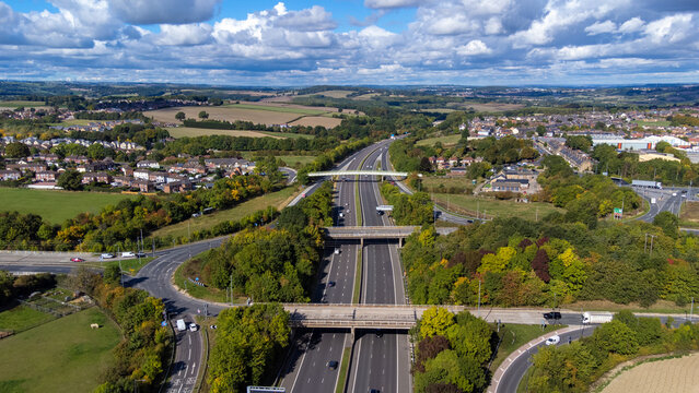 Aerial drone photo of the busy M1 motorway with three bridges crossing over the highway in the village of Barnsley in Sheffield UK in the summer time on a bright sunny summers day.