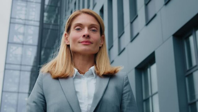 Female portrait close-up caucasian business woman standing outdoors looking away successful confident businesswoman satisfied client turns to camera smiling poses against backdrop of office building