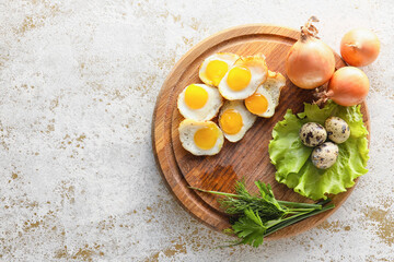 Wooden board with fried quail eggs on light background