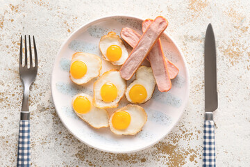 Plate of tasty fried quail eggs with sausages on light background, closeup