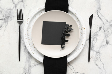 Elegant table setting with blank card and black napkin on light background