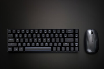 Black gaming compact ergonomic computer keyboard and computer mouse on a dark background. Wireless...