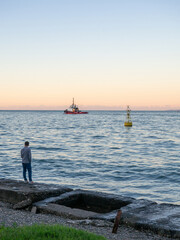 Fototapeta na wymiar Port area. Tugboat on the road. A buoy in the bay of the port. Marine urban landscape.