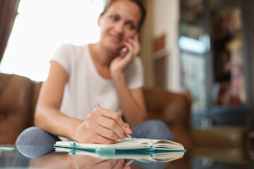 Woman speaking on phone and writing something on notepad