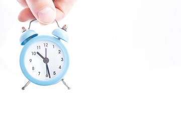 Small alarm clock in hand on a white background.