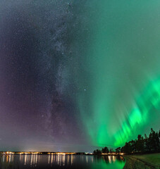 Breathtaking Milky Way galaxy close to Aurora, scenic vertical photo of Northern Lights over calm...
