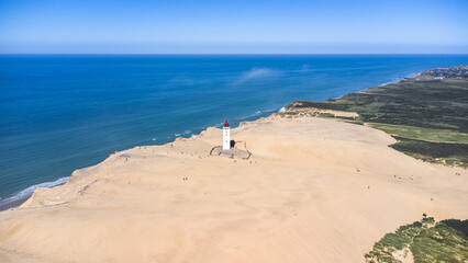 Obraz na płótnie Canvas white lighthouse at the sea surrounded by sand