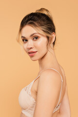 portrait of young woman with natural makeup posing in lace bra isolated on beige