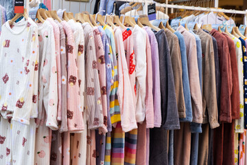 A shopping rank filled with clothes, pajamas and robes. Bunch of clothes of different colors for sale. Cheep clothing and fast fashion theme