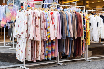 A shopping rank filled with clothes, pajamas and robes. Bunch of clothes of different colors for sale. Cheep clothing and fast fashion theme