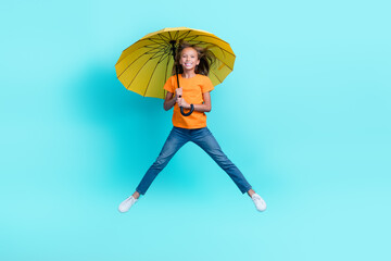 Full body size photo of charming excited positive carefree preteen girl jumping flying windy air parasol enjoy isolated on aquamarine color background © deagreez