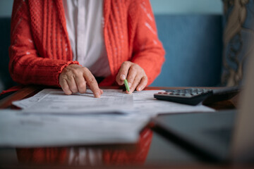 The hands of an elderly woman with a calculator and a lot of utility bills. Pensioner and payment...