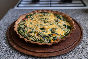 Delicious vegetable tart with gratin cheese on a wooden board - obrazy, fototapety, plakaty