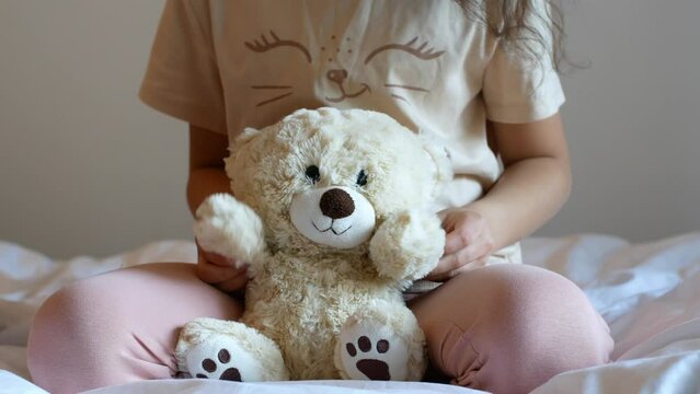 A little girl plays with a teddy bear. Childhood and toys.