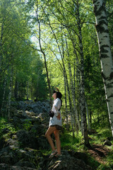 Naklejka na ściany i meble Girl tourist posing against the background of stones, rocks, nature. Day, forest.