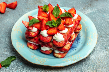 Italian dessert tiramisu cake with fresh strawberry, biscuit and whipped cream and mint on a dark background, Vegan lactose free dessert