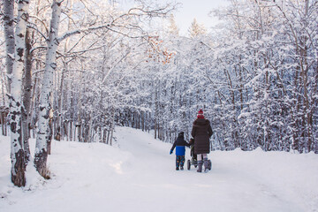 Mother and son walking along a snowy footpath in a forest