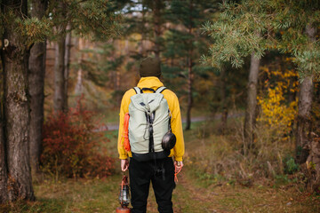Tourist on a hiking trail in the forest with a backpack and a lamp.