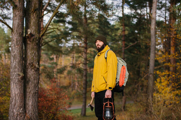 Tourist on a hiking trail in the forest with a backpack and a lamp.