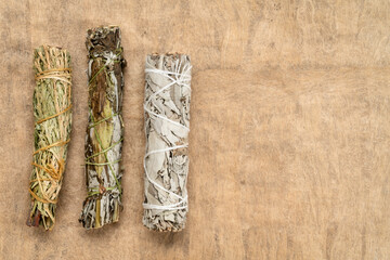 white sage, mugwort and siskiyou cedar incense bundles on a textured bark paper with a copy space, aromatherapy concept