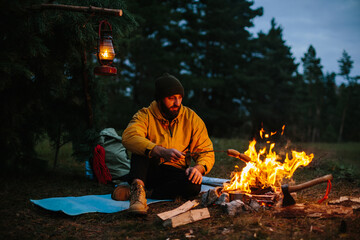 A lonely wanderer is having dinner in the mountains by a campfire.