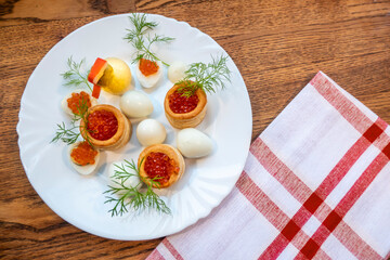 background of red caviar on dsrk wooden surface. tartlets with red caviar. edible egg yolk chicken figurine for decorating dishes