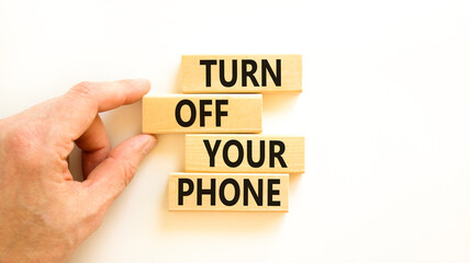 Turn off your phone symbol. Concept words Turn off your phone on wooden blocks. Beautiful white table white background. Businessman hand. Business psychological turn off your phone concept. Copy space