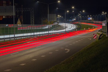 Cars blurred lighting traces on night on roadway from Riga to resort city Jurmala. Shot from bridge over way.