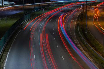 Cars blurred lighting traces on night on roadway from Riga to resort city Jurmala. Shot from bridge over way.