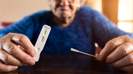 Close-up grandma hand holding a buffer dropper for seft detection of coronavirus