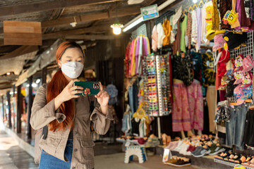 Hipster woman traveler with mask and backpack taking photo by mobile in ayothaya thailand, Travel Holiday Relaxation Concept