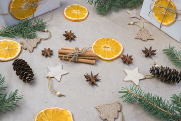 New Year's composition. On beige craft paper, gift boxes, dry orange slices, pine cones, cinnamon, cloves, spruce branches. Cozy Christmas concept.