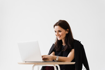 Young woman have a break, watching online videos and trainings on laptop, preparing for conference. Cheerful girl with laptop typing text and chatting with friends and family in white cafe.