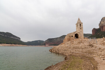 Fototapeta na wymiar Reservoir with little water in which a church can be seen due to the drought and the little rain effect of global warming