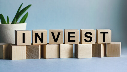The inscription INVEST on wooden cubes isolated on a blue background, the concept of business and finance.