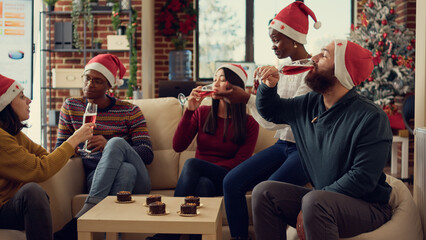 Diverse people clinking glasses with alcohol to say cheers, celebrating christmas holiday at office...