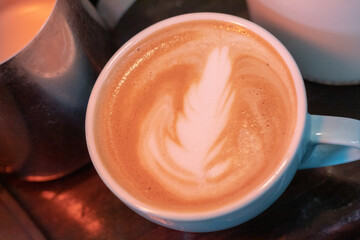 Close up of a cup of coffee in a coffee shop with a simple latte art drawing