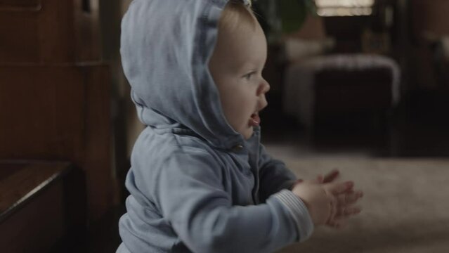 Close up of happy baby boy sitting on floor clapping hands / Cedar Hills, Utah, United States