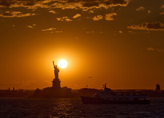 The Statue of Liberty at sunset with the sun just above Liberty's shoulder