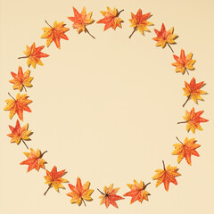 Autumn round frame made of orange and yellow leaves against a beige background. Minimal season nature concept. Copy space.