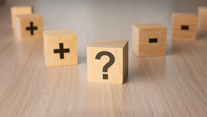 sign question mark, plus, minus sign on the faces of a wooden cube. mini wood cubes on wooden background