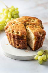 Homemade biscuit cake or pie with white fresh grapes on a white marble background