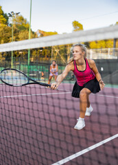 Obraz premium Female player playing tennis in tennis court outdoor behind the net